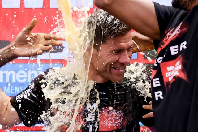 Bayer Leverkusen’s head coach Xabi Alonso is doused with beer by his players at his post-match press conference after the club clinched the Bundesliga title