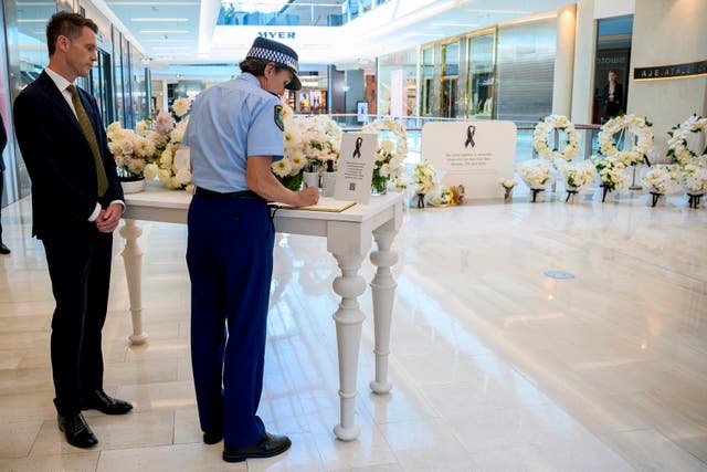 New South Wales Premier Chris Minns, left, watches as the NSW Police Commissioner Karen Webb signs a condolence book while visiting a memorial at Westfield shopping centre at Bondi Junction in Sydney 