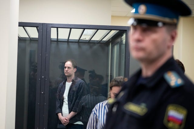 Wall Street Journal reporter Evan Gershkovich, left, stands in a glass cage in a courtroom at the First Appeals Court of General Jurisdiction in Moscow, Russia