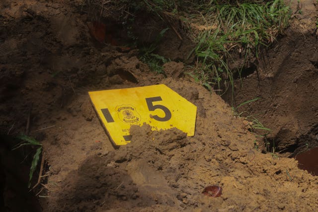 A label with the number 5 to mark one of nine unidentified migrants, sits on a freshly dug grave during a burial service, at Sao Jorge cemetery, in Belem
