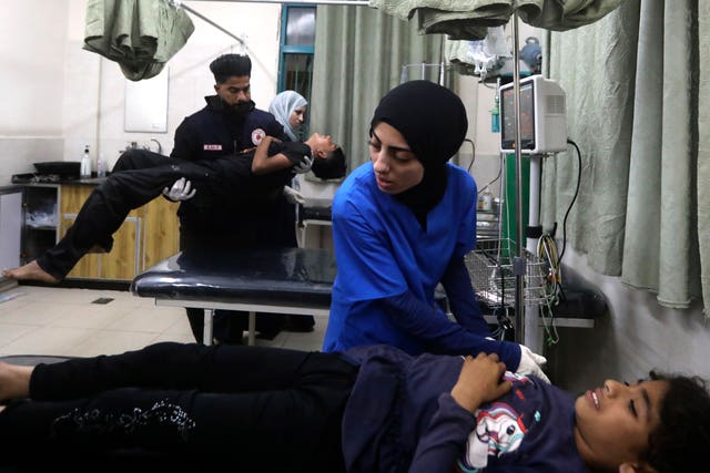 Palestinian medics treat a wounded person as the other one carries a young wounded in the Israeli bombardment of the Gaza Strip at the Kuwaiti Hospital in Rafah refugee camp, southern Gaza Strip