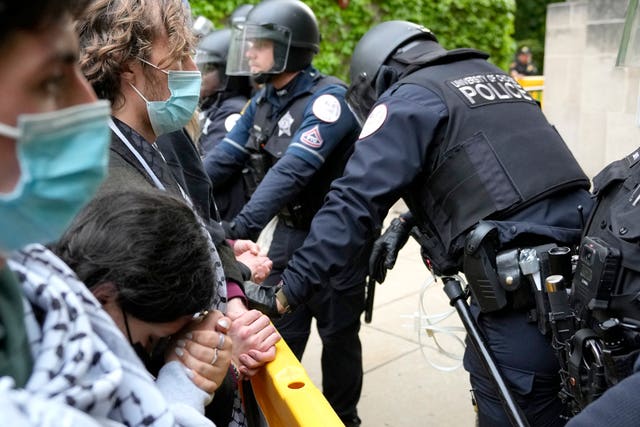 A pro-Palestinian protester rests her head on her clasped hands while she stands before police officers at the University of Chicago 