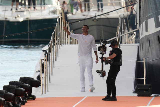 French Olympic swimmer Florent Manaudou holds the Olympic torch after leaving the Belem, the three-masted sailing ship in the Old Port of Marseille, southern France