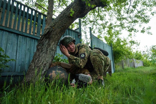 A police officer takes cover during Russian shelling in Vovchansk, Ukraine