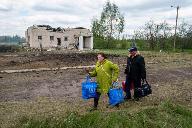 People walk with their belongings to the evacuation point in front of a building that was damaged by a Russian air strike in Vilcha, near Vovchansk, Ukraine 