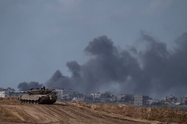 Backdropped by smoke rising to the sky after an explosion in the Gaza Strip, an Israeli tank stands near the Israel-Gaza border as seen from southern Israel 