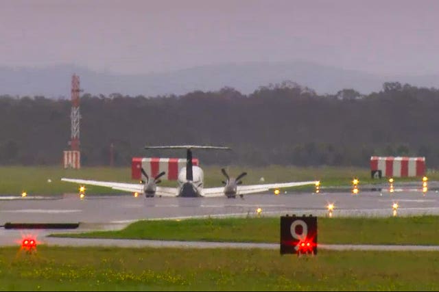 In this image taken from video, a light plane with three people aboard lands safely without landing gear at Newcastle Airport, Australia