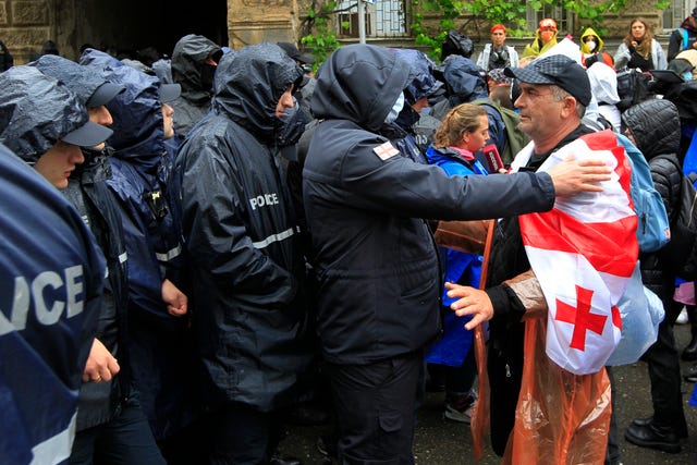 A demonstrator wears a national flag as he argues with the police