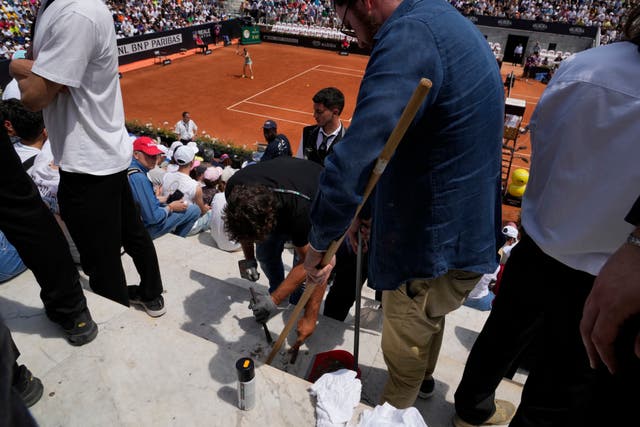 Ground staff remove glue used by a climate activist during Madison Keys' win at the Italian Open