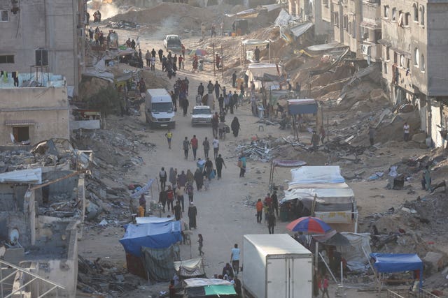 Palestinians walk through the debris after an Israeli air and ground offensive in Khan Younis, southern Gaza Strip