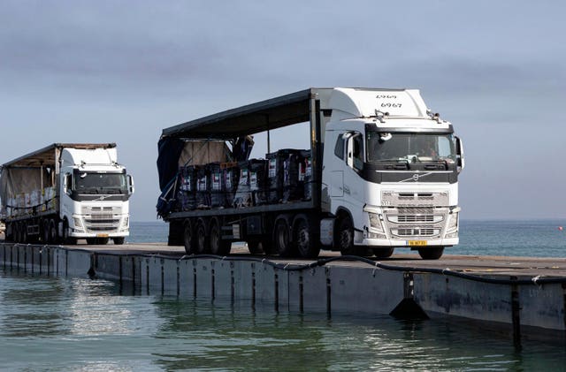 Trucks loaded with humanitarian aid from the United Arab Emirates and the United States Agency for International Development cross the Trident Pier before arriving on the beach on the Gaza Strip on May 17 2024 