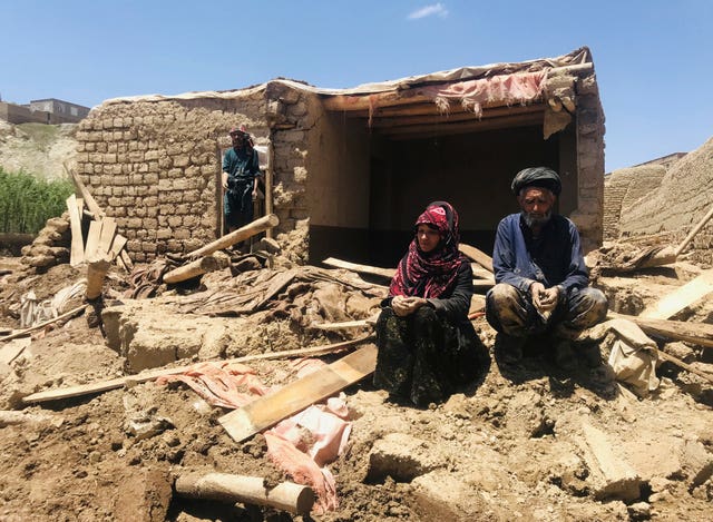 An Afghan couple sit near their damaged home after the heavy flooding