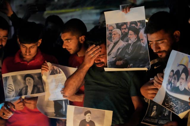 A Shiite Muslim weeps while holding photos of Iranian president Ebrahim Raisi