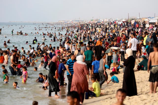 Palestinian family members displaced by the ongoing war with Israel on the beach during a heatwave in southern Gaza 