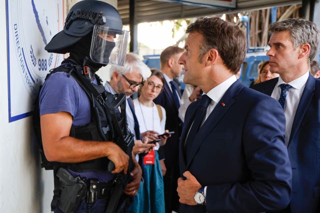 The French president speaking to a policeman at the central police station in Noumea 
