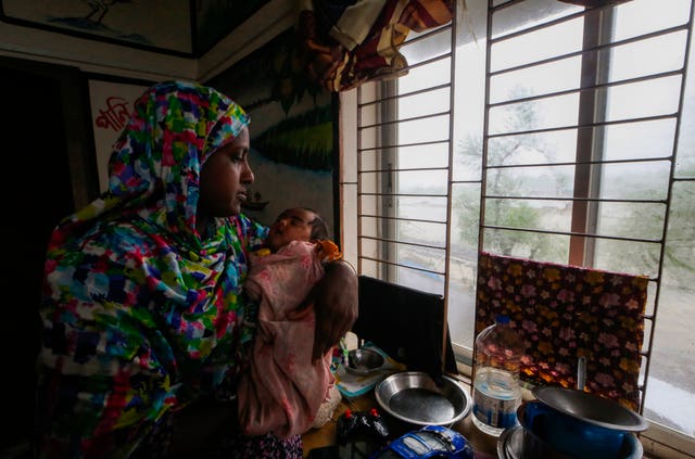 An evacuated woman and infant sit inside a shelter after Remal lashed Bangladesh’s southern coast