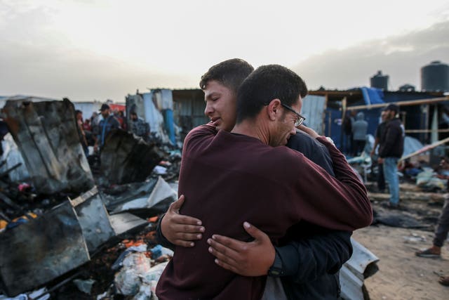 Palestinians react next to the destruction after an Israeli strike in Rafah