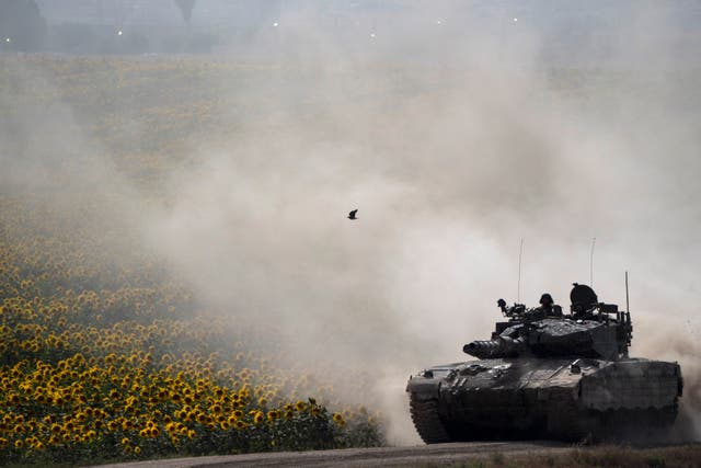 Israeli soldiers move on the top of a tank near the Israeli-Gaza border, as seen from southern Israel