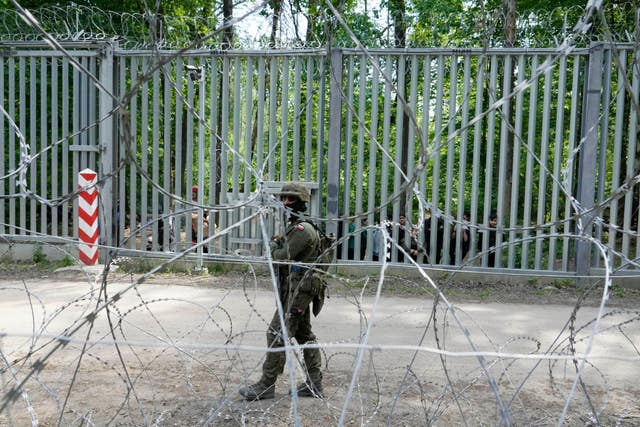 A Polish soldier patrols the metal barrier border with Belarus