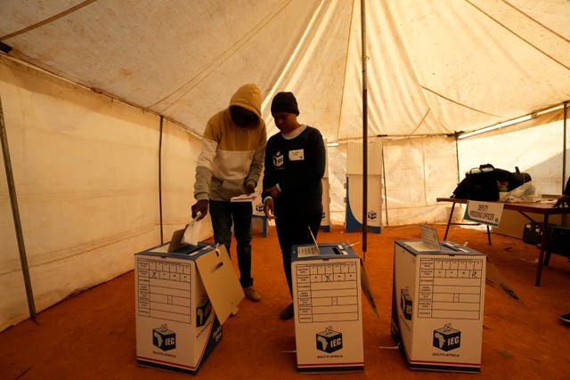 A man assisted by an electoral worker casts his ballot at a polling station in Alexandra, near Johannesburg, South Africa