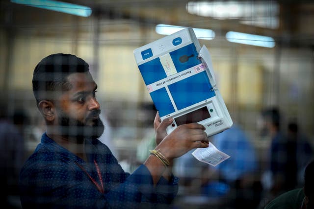 An election official shows the electronic voting machine to the agents of political parties at a counting centre in Guwahati, India