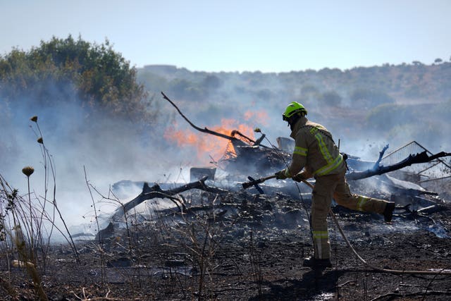 A firefighter runs towards flames on churned ground