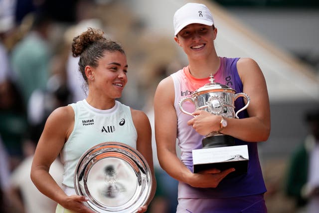 Jasmine Paolini and Iga Swiatek stand next to each other holding their French Open trophies