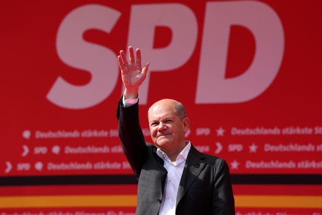 Olaf Scholz stands with arm raised as he waves to supporters