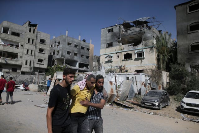 Palestinians help a wounded man after Israeli strikes in Nuseirat refugee camp, Gaza Strip