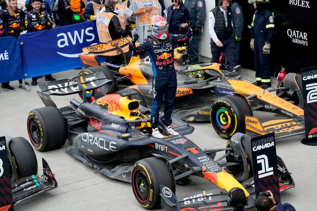 Max Verstappen stands on his car as he poses for pictures following his win in Canada