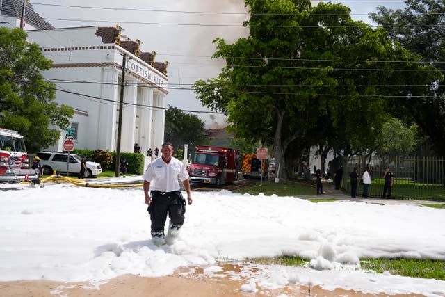 A firefighter walks from the scene of the blaze in Miami with foam across the ground 