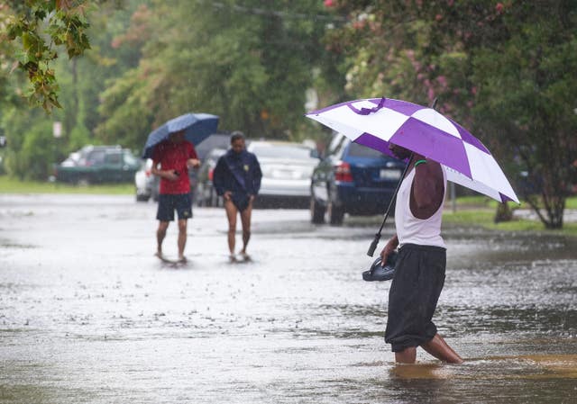 People walk through flood waters at the intersection at Simons Street and Rutledge Avenue