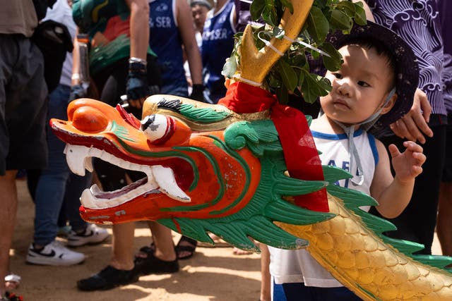 A little boy looks at a carved dragon head