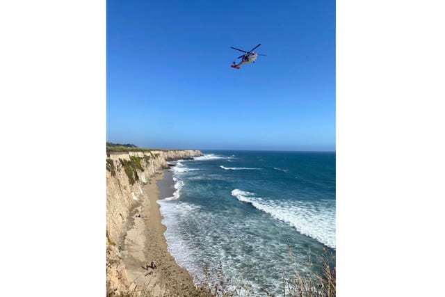 The scene of the rescue of a kite surfer on a beach under a cliff