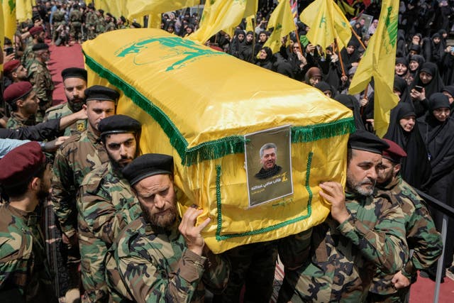 Hezbollah fighters carry a yellow and green coffin bearing their commander