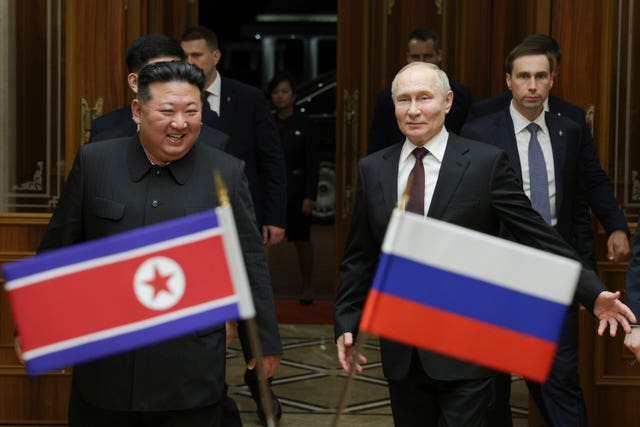 Kim Jong Un and Vladimir Putin carry each other's national flags