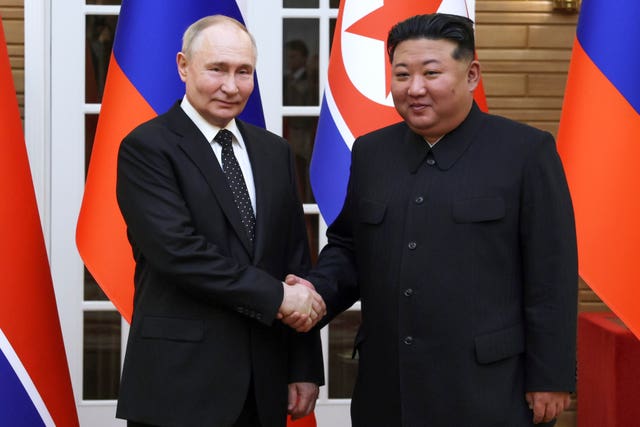 Mr Putin shakes Mr Kim by the hand
