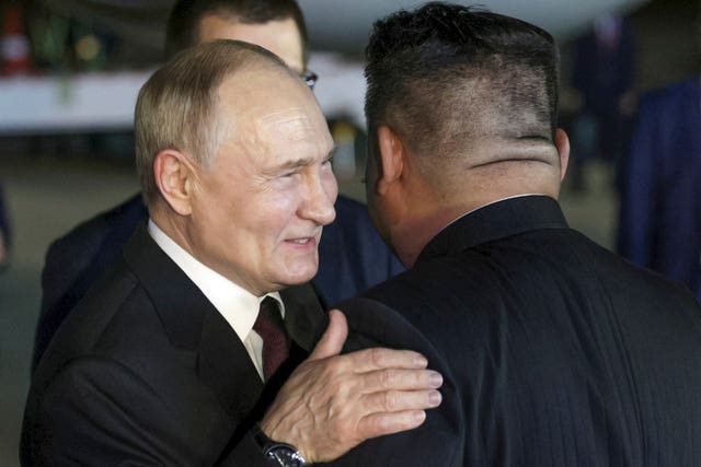 Mr Putin smiles and puts a hand on Mr Kim's shoulder