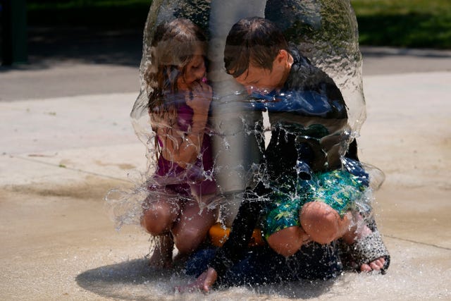 Two children play under a water sprinkler at Broad Ripple Park in Indianapolis