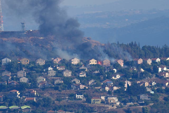 Fires and black smoke rise from between the houses of the northern Israeli border town of Metula