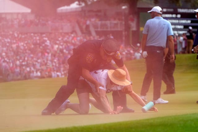 A protester is tackled by a police officer at the Travelers Championship in Connecticut