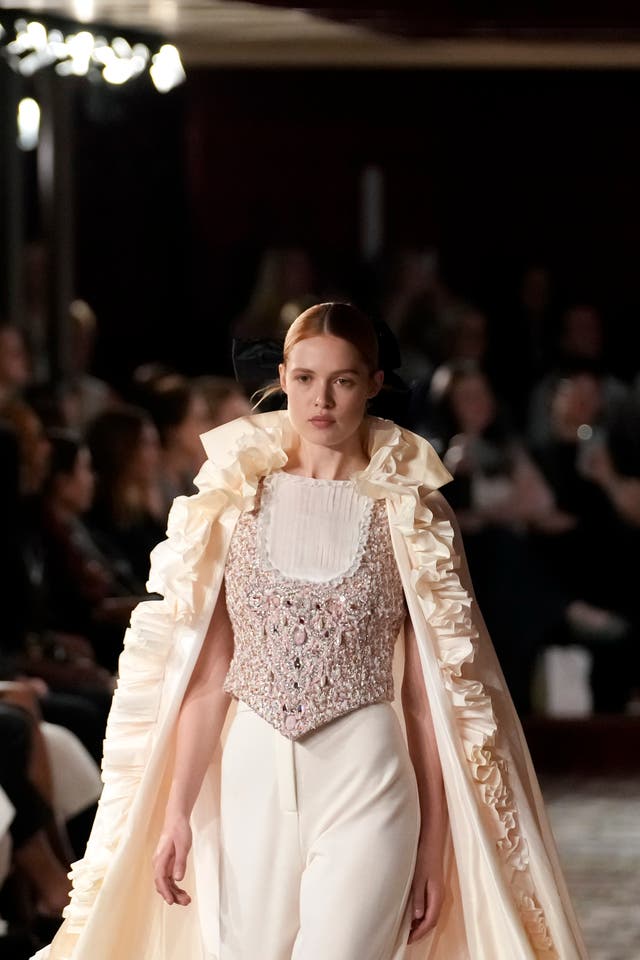 A woman wears a Chanel outfit consisting of a jewel encrusted corset and cape
