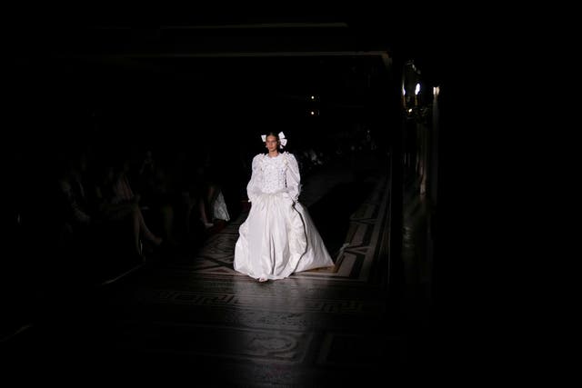 Model Angelina Kendall wears a white Princess Diana-inspired wedding dress with a drop hem waist and ruffled flowers