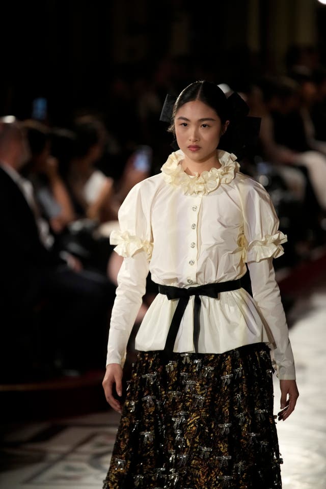 A model walks down the catwalk wearing an outfit of top and skirt with an Elizabethan court feel