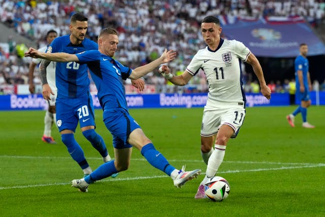 Phil Foden, right, moves the ball as Slovenia’s Zan Karnicnik, center, reaches in and Petar Stojanovic watches during a Group C match between the England and Slovenia