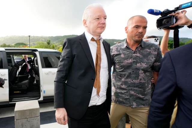 WikiLeaks founder Julian Assange, left, is escorted as he arrives at the United States courthouse, in Saipan, Mariana Islands, Wednesday, June 26 2024.