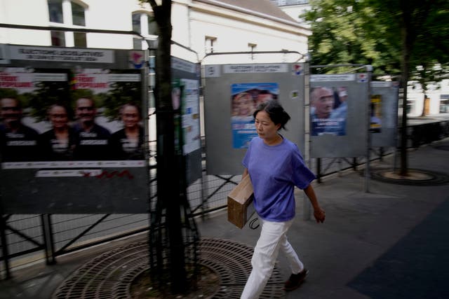 A woman walks past campaign boards for the upcoming parliamentary elections in Paris 
