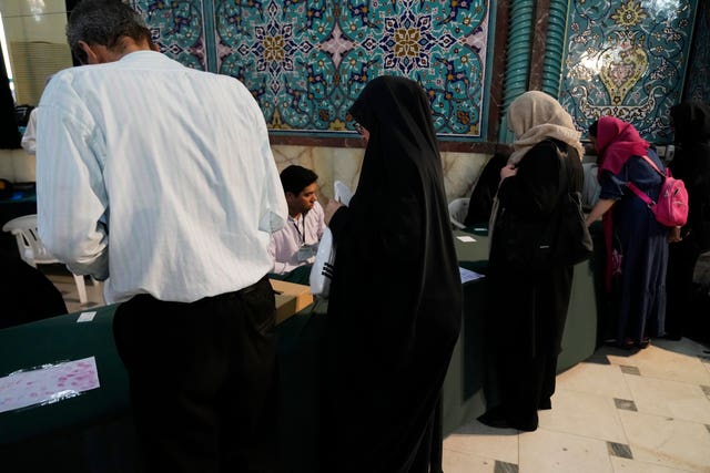 People receive their ballot paper during the Iranian presidential election at a polling station in Tehran