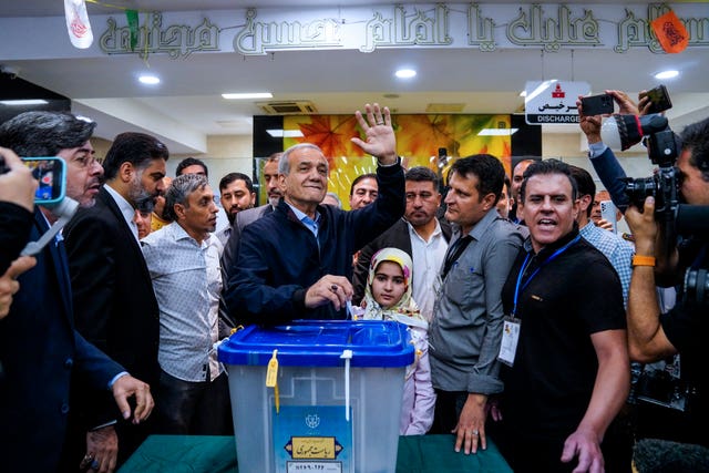 Reformist candidate for the Iranian presidential election Masoud Pezeshkian waves as he casts his ballot