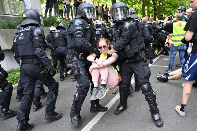 Police carry a protester as they break up a blockade in Essen, where the AfD is holding a convention